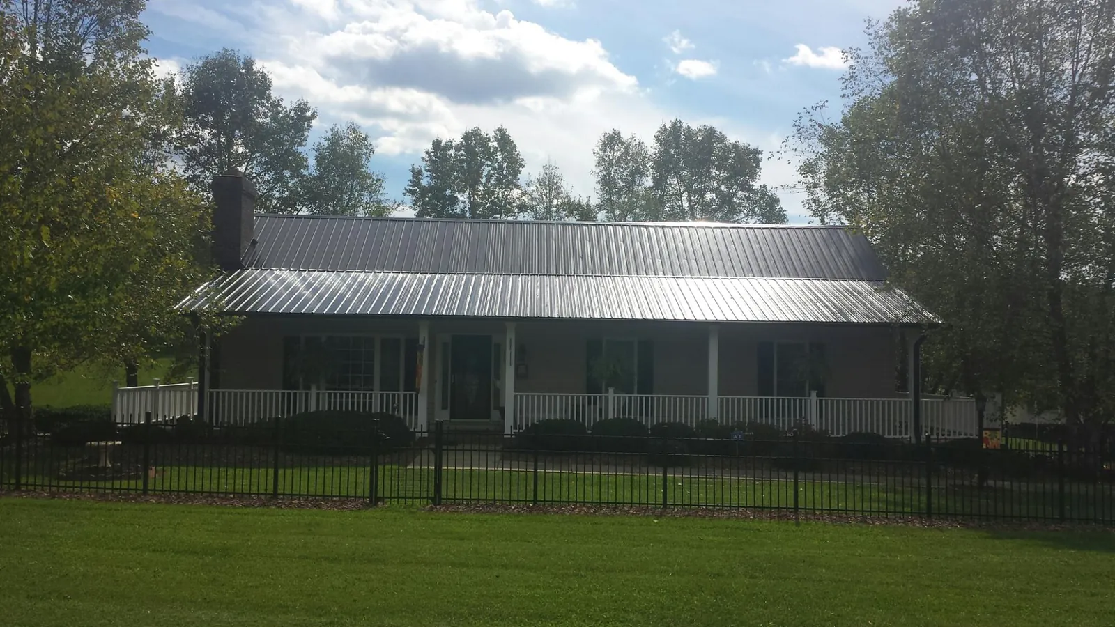 Gray metal roof on a brick ranch with a full width front porch — Gutter Guard Installation work by our crew in Mabel