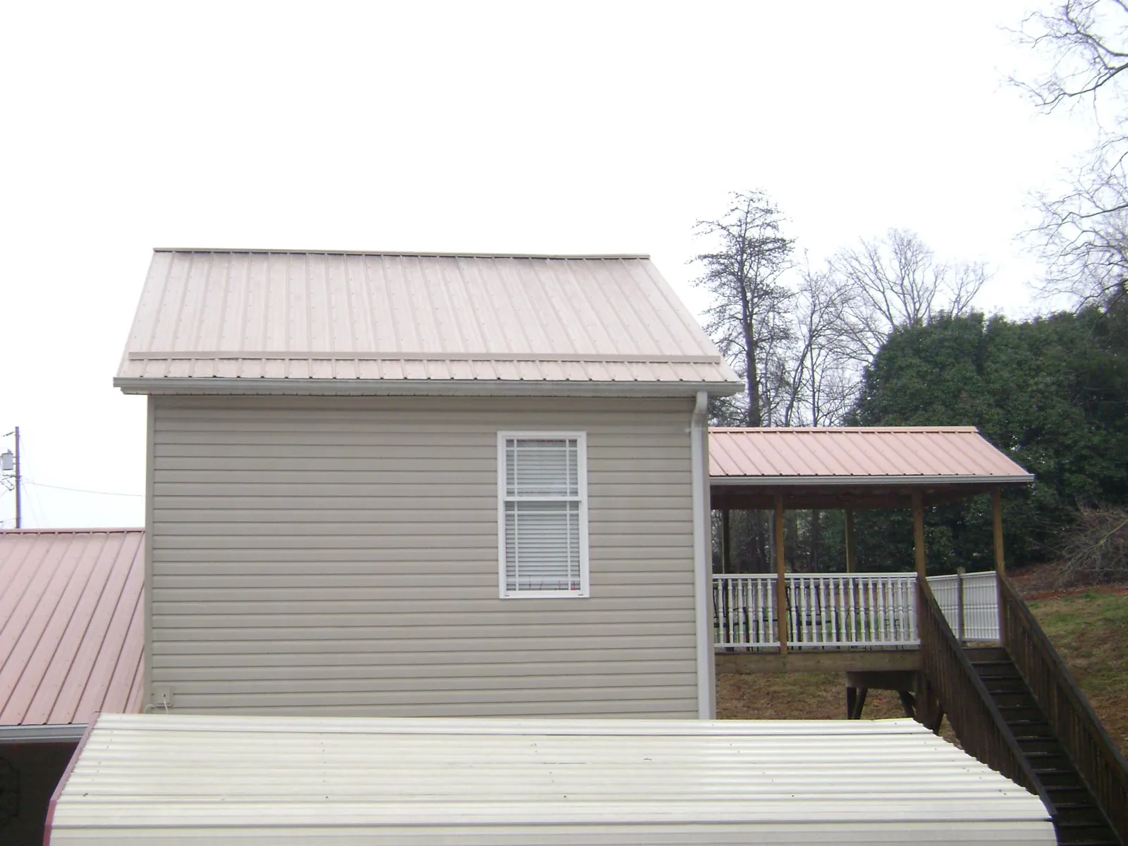 Tan metal roofs on a two story addition and attached porch, from a Roof Replacement job in Mabel